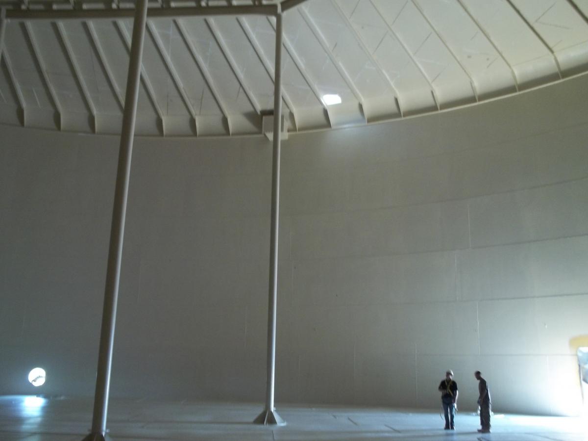 Large empty industrial round building interior with 2 people conversing